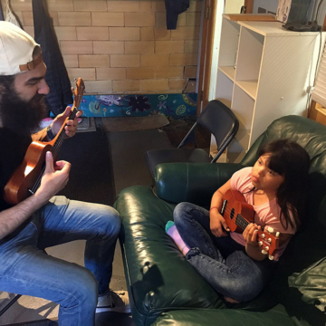 Staff teaching a student how to play a ukulele