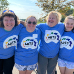 Four people wearing the Arts in Motion palette logo blue t-shirt.