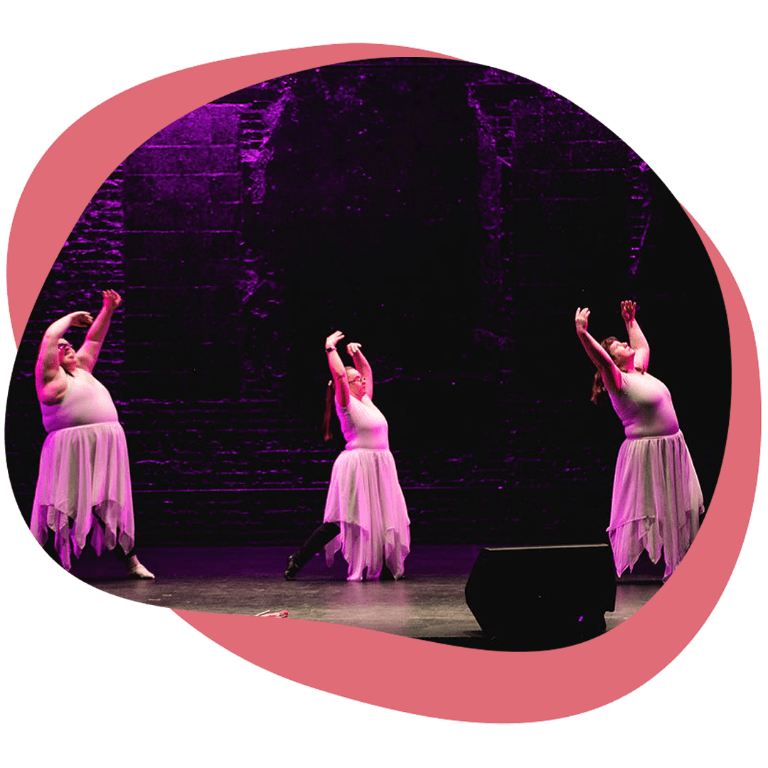Three dancers wearing leotards performing on a stage.