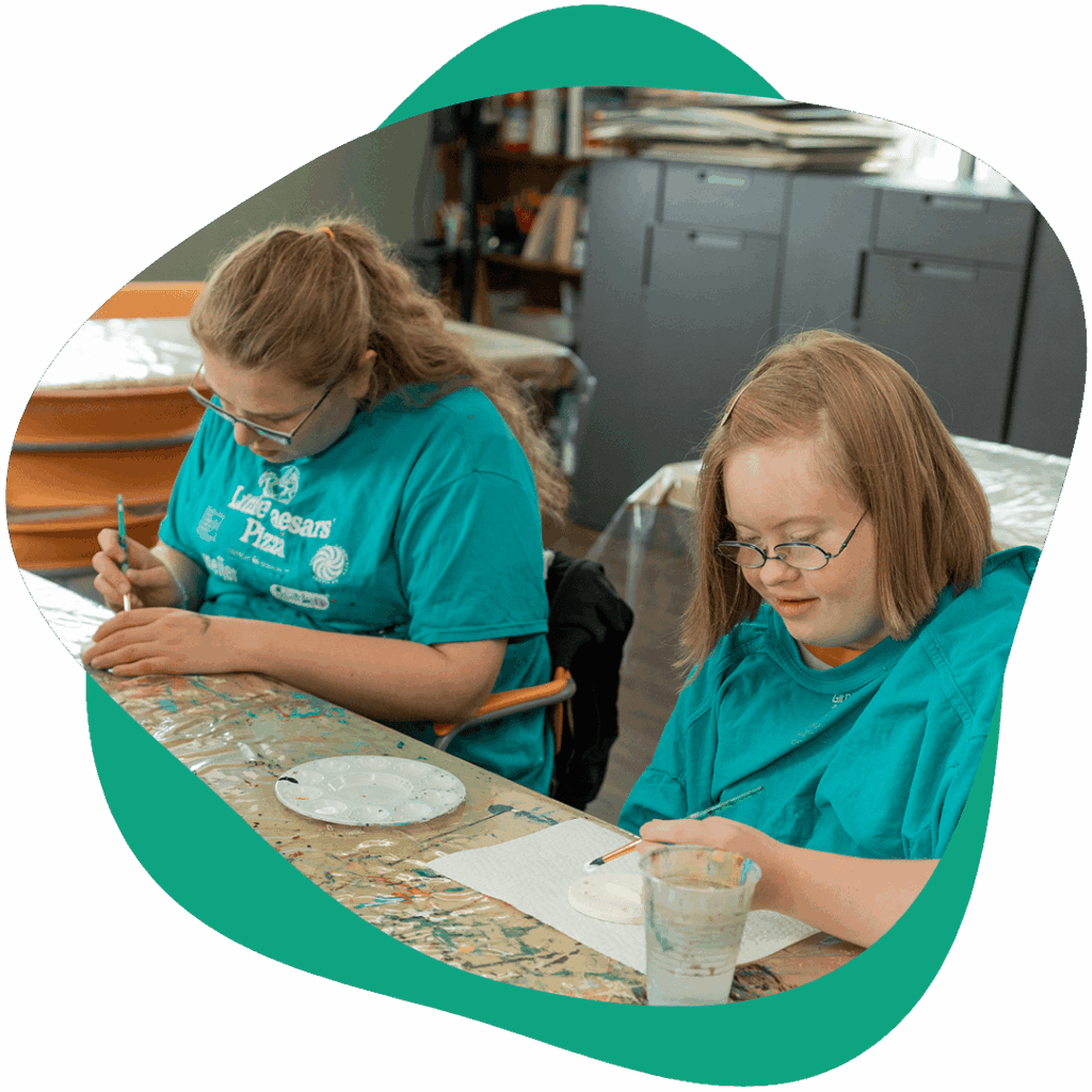 Two art students painting at a table.
